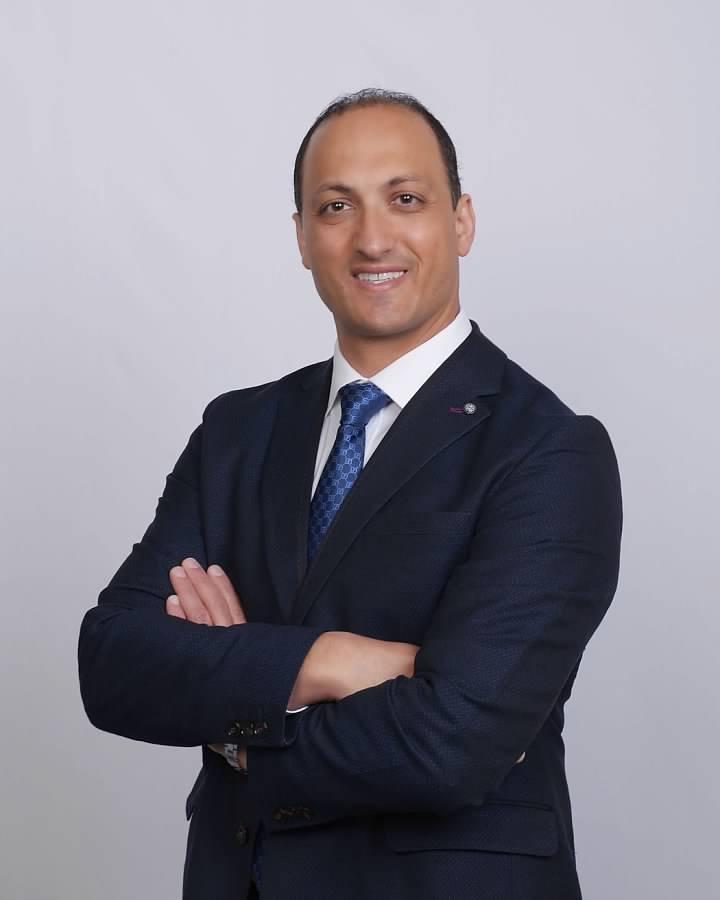 Standing professional portrait of Dr. Ramis Gheith in a navy suit